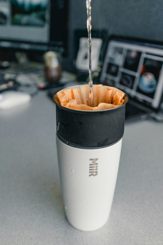 white and black travel mug on gray surface