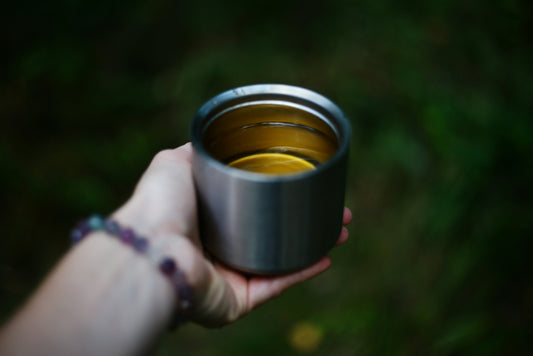A hand holds a steel cup outdoors